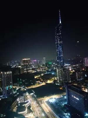a lit up skyscraper in a city at night at Rainfall Suite And Service at Time Squre KL in Kuala Lumpur