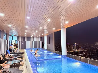 a pool on the top of a building with people sitting in chairs at Colony Greenfield Suites Klcc in Kuala Lumpur
