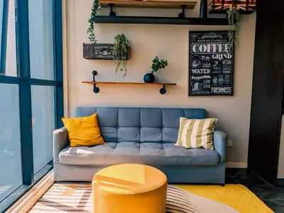 a living room with a blue couch and yellow pillows at Skyline Homes by Myfly247 in Kuala Lumpur