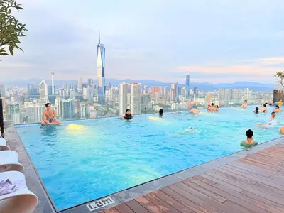 a pool on the roof of a building with people in it at COzy Suite KL Sentral By Riveria City in Kuala Lumpur