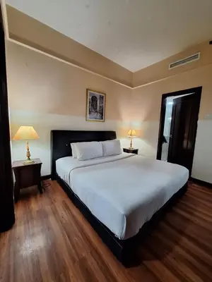 a bedroom with a large white bed and two lamps at KL Times Square Hotel Service Suite in Kuala Lumpur
