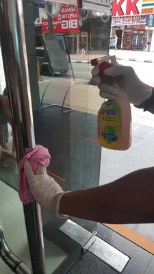 a person is cleaning a glass door with a towel at Cardogan Hotel in Kuala Lumpur