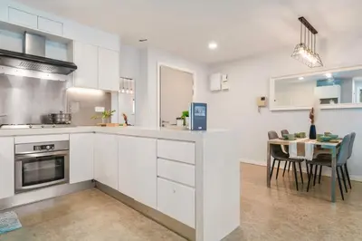 a kitchen with white cabinets and a dining table at Bintang Fairlane near Pavillion Bukit Bintang in Kuala Lumpur