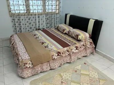 a bed with a quilt and pillows on it at Baiduri Homestay in Kuala Lumpur
