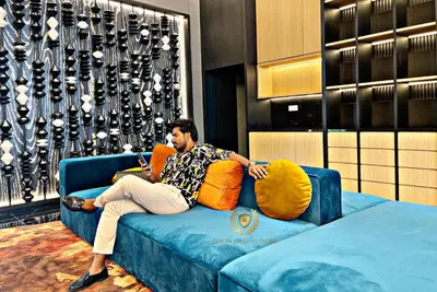 a man sitting on a couch with a cell phone at The Majestic Gen Luxury Suites KLCC in Kuala Lumpur