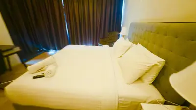 a hotel room with a bed with white sheets and pillows at Star Residence Suites KLCC Sky pools in Kuala Lumpur