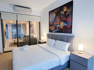 a bedroom with a white bed with a painting on the wall at Eaton Residence KLCC Kuala Lumpur in Kuala Lumpur