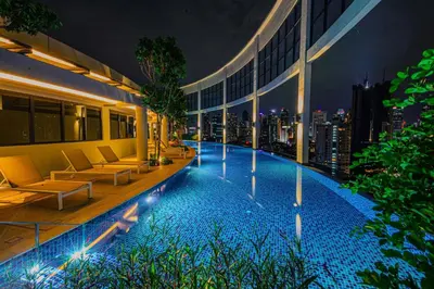 a hotel swimming pool with a city skyline at night at The Atrium at Jalan Ampang by OKBnB- Modern Cozy 3 Bedroom Apartment 4 Mins to KLCC in Kuala Lumpur