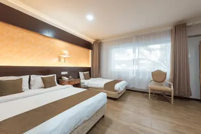 a hotel room with two beds and a chair at Hotel Grand Orchard in Kuala Lumpur