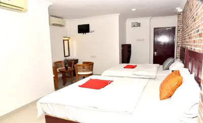 a bedroom with two beds and a dining room at J Hotel Masjid India KL in Kuala Lumpur