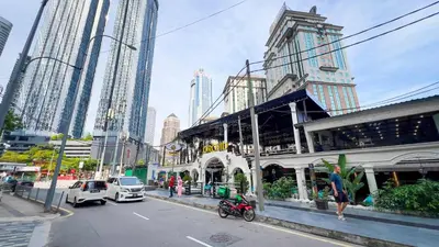 a city street with tall buildings and a woman walking on the street at Scarletz Suite KLCC 2 in Kuala Lumpur