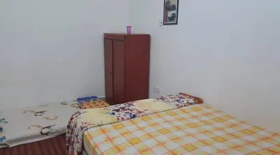 a bedroom with two beds and a cabinet at Zam Zam Homestay in Kuala Lumpur