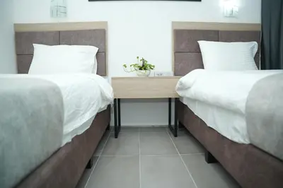 two beds with white sheets and a wooden table between them at Arena Suites Kuala Lumpur in Kuala Lumpur