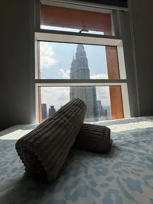 a bed with a large window with a view of a building at Nest In The Sky in Kuala Lumpur