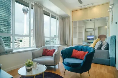 a living room with a blue couch and two chairs at A Cozy & Comfy Studio in KLCC with KL Tower View in Kuala Lumpur