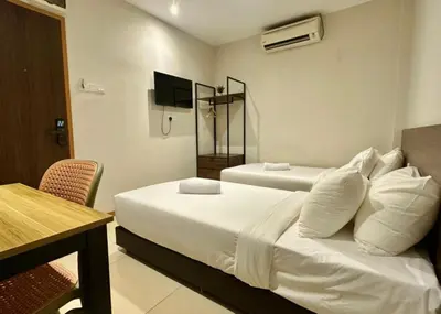 a hotel room with two beds and a table and a television at Swing & Pillows - Chow Kit Road, Kuala Lumpur in Kuala Lumpur
