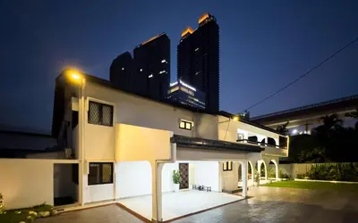 a white house with two tall buildings in the background at Damansara Heights Luxury Villa with Private Pool in Kuala Lumpur