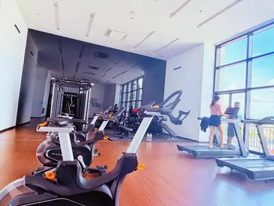 a woman in a gym with treadmills and exercise bikes at Chamber Luxury Serviced Suites KL in Kuala Lumpur