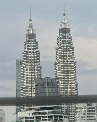 three tall skyscrapers in a city with buildings at Majestic Residences KLCC By Cozy in Kuala Lumpur
