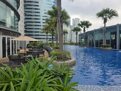 a large swimming pool with palm trees and buildings at Vortex suites klcc by KAZI in Kuala Lumpur