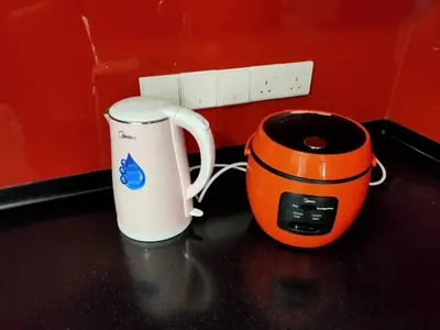 an orange and white coffee mug next to a toaster at Kuala Lumpur Mont Kiara Arcoris SOHO 5 Pax, Walk to Mall, Pool, WIFI in Kuala Lumpur
