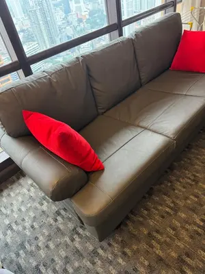 a brown couch with two red pillows on it at Visitor Suites At Times Square Kuala Lumpur in Kuala Lumpur