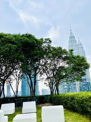 a group of white chairs and trees in a park at KLCC Service Suites at Mews in Kuala Lumpur
