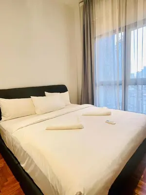 a large bed with white sheets and a window at KLCC Service Suites at Mews in Kuala Lumpur