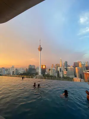 a group of people swimming in a infinity pool with a city skyline at Ceylonz suites Klcc by StayLa in Kuala Lumpur