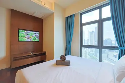 a bedroom with a large bed with a television on it at 8 min walk to Pavilion KL - Infinity Pool w TRX view in Kuala Lumpur