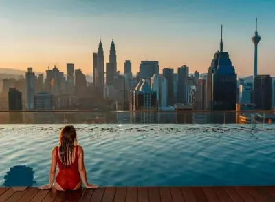 a woman sitting in a infinity pool overlooking a city at Infinity Sky Pool, Regalia Suite KLCC in Kuala Lumpur