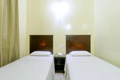two beds in a room with white sheets at Nan Yeang Hotel Petaling Street in Kuala Lumpur