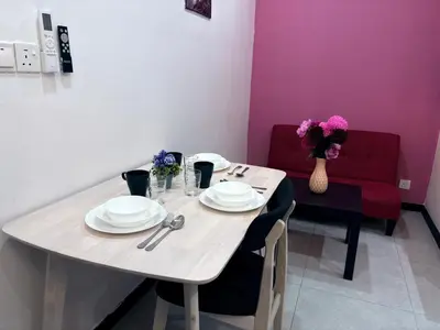 a dining room table with plates and a red couch at Neu suite, Family Unit - Jelatek LRT Gleneagles Hospital in Kuala Lumpur