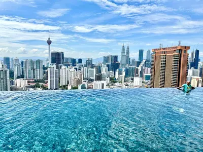 a woman sitting in a infinity pool overlooking a city at Lucentia residence bukit Bintang city centar in Kuala Lumpur