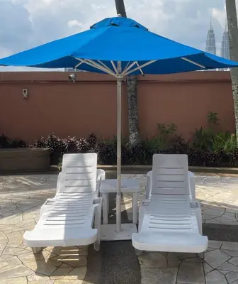 two white chairs and a blue umbrella on a patio at Elegant Apartment at Times Square in Kuala Lumpur