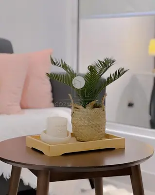 a table with a potted plant on it next to a bed at Arte Mont Kiara by CozyVista Suites in Kuala Lumpur