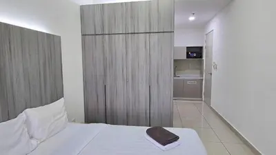 a bedroom with a white bed with a wooden door at Trion KL Star Suites in Kuala Lumpur