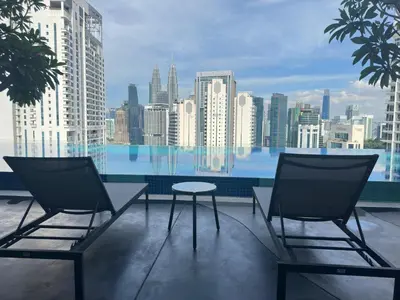 two chairs and a table on a balcony with a city skyline at Luxury couple suite 307A at Majestic Residence in Kuala Lumpur