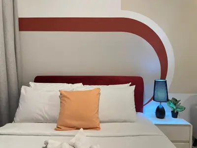 a bed with an orange pillow and a blue lamp at Luxury couple suite 251B at KLCC in Kuala Lumpur