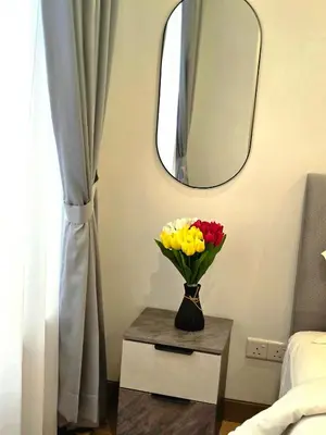 a vase of flowers on a table with a mirror at Lucentia Residence Infinity swimming pool BY Lalaport in Kuala Lumpur