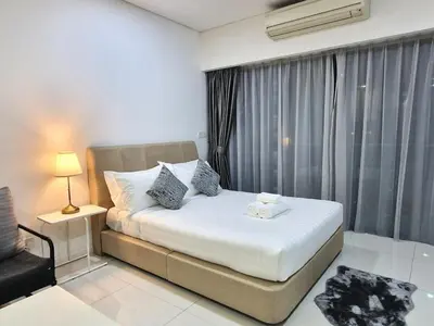 a bedroom with a bed and a chair and a window at Mercu Summer Suites KLCC By ATIQ in Kuala Lumpur