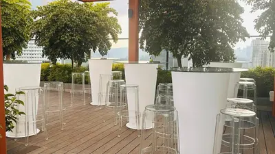 a row of chairs and tables on a deck with trees at Cozy suite for couple 297A at KLCC in Kuala Lumpur