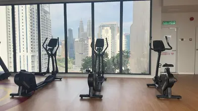a gym with cardio equipment in front of a large window at Private family suite 27171BR at KLCC in Kuala Lumpur