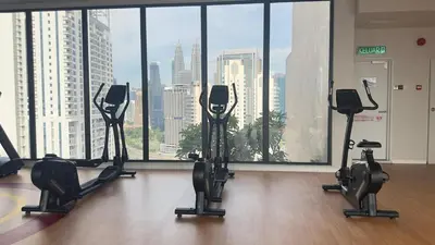 a gym with cardio equipment in front of a large window at Couple luxury suite 275B at Majestic Residence in Kuala Lumpur