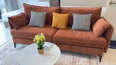 a brown couch with pillows and a white table at Private family service suite 2613A1BR at Majestic Residence in Kuala Lumpur