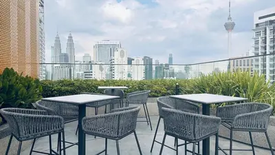a patio with tables and chairs and a city skyline at Cozy suite for couple 275A at Majestic Residence in Kuala Lumpur