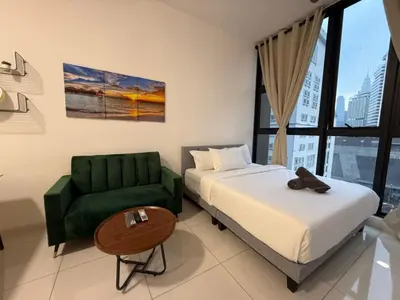 a hotel room with a bed and a green couch at Majestic Residences KLCC By Moonlight in Kuala Lumpur