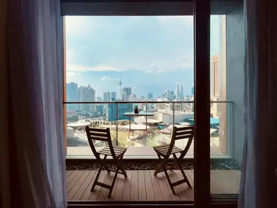 a balcony with two chairs and a view of a city at Lucentia Residences By ONZO in Kuala Lumpur