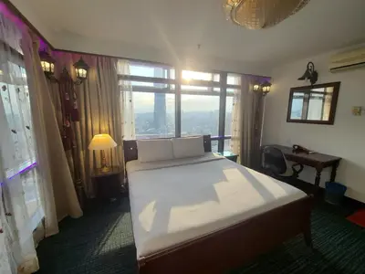 a bedroom with a large bed and a desk and window at Grand Lumia Suite At Times Square KL in Kuala Lumpur