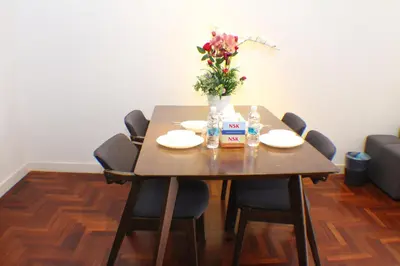 a wooden table with chairs and a vase of flowers at The Mews KLCC Service Suites in Kuala Lumpur
